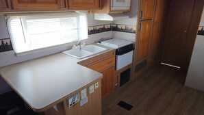 Una cocina compacta con ventana, lavamanos y armarios de madera.