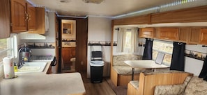 A compact RV interior with a kitchenette, a dining area, and a small bathroom.