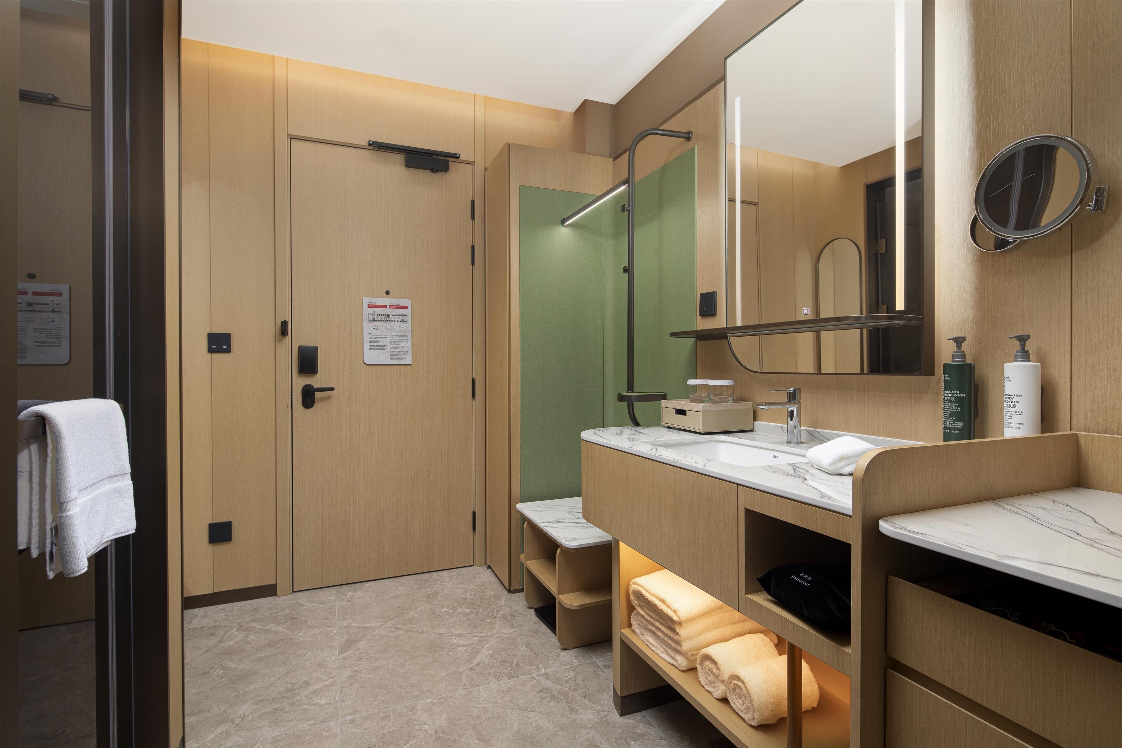 A modern bathroom with a marble sink, a large mirror, and a towel rack.