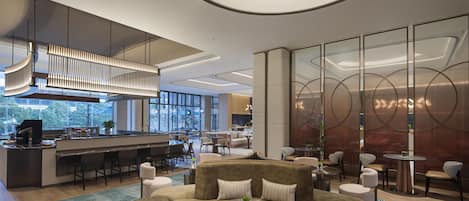 A modern lounge area with a bar, seating arrangements, and a view of the outdoors.
