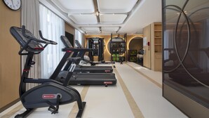 A gym with treadmills, weight machines, and a large mirror. - Hilton Garden Inn Zhangjiajie Tianmen Mountain (Zhangjiajie)