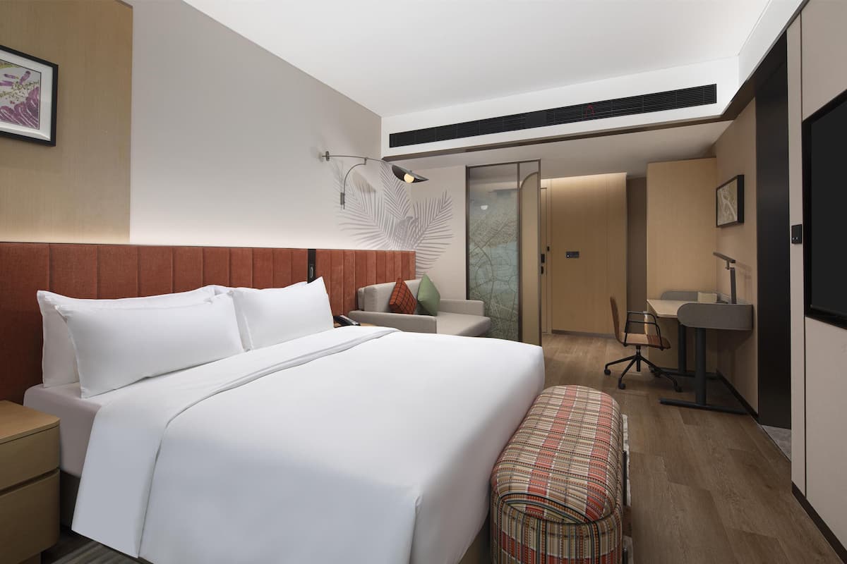 Una habitación de hotel moderna con una cama grande, un escritorio y una zona de estar.