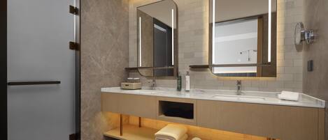 A modern bathroom with two sinks, a mirror, and a towel rack.