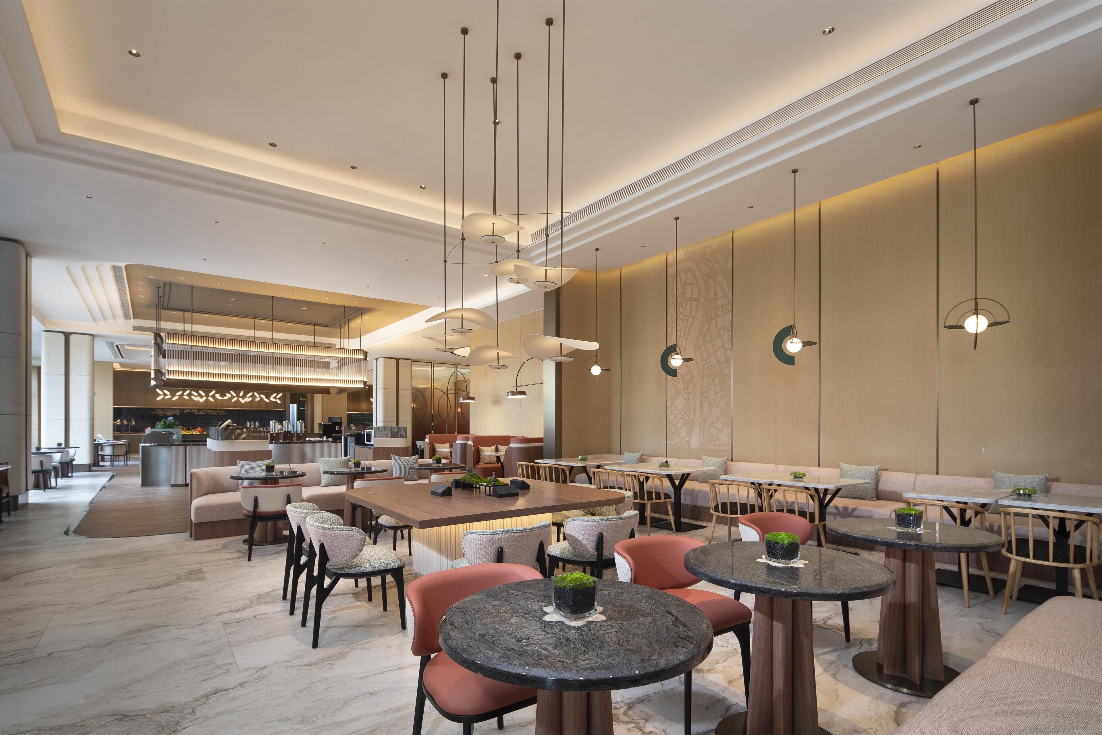Un restaurant moderne avec des tables et des chaises rondes, un coin bar et des luminaires suspendus.