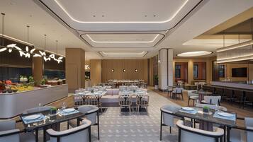 Un espace de restauration moderne dans un hôtel, offrant de nombreuses options de sièges, notamment des tables et des banquettes, ainsi qu’un bar central.