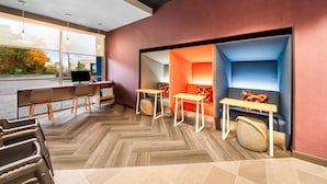 Een moderne hotellobby met een visgraatvloer, een receptiebalie, een zithoek en grote ramen met uitzicht op het buitengebied.