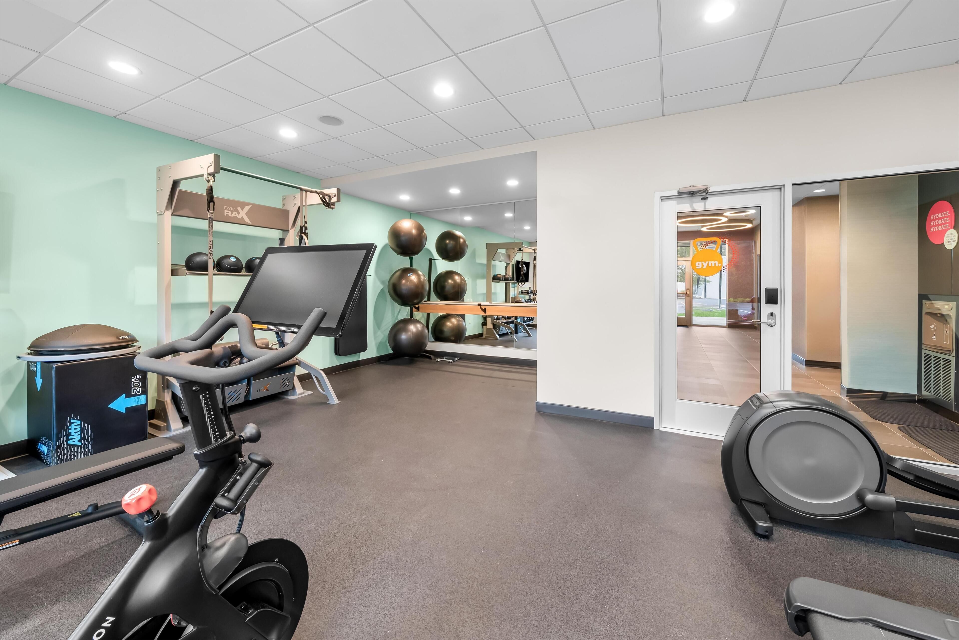 A gym with exercise equipment, a treadmill, and a wall-mounted TV.