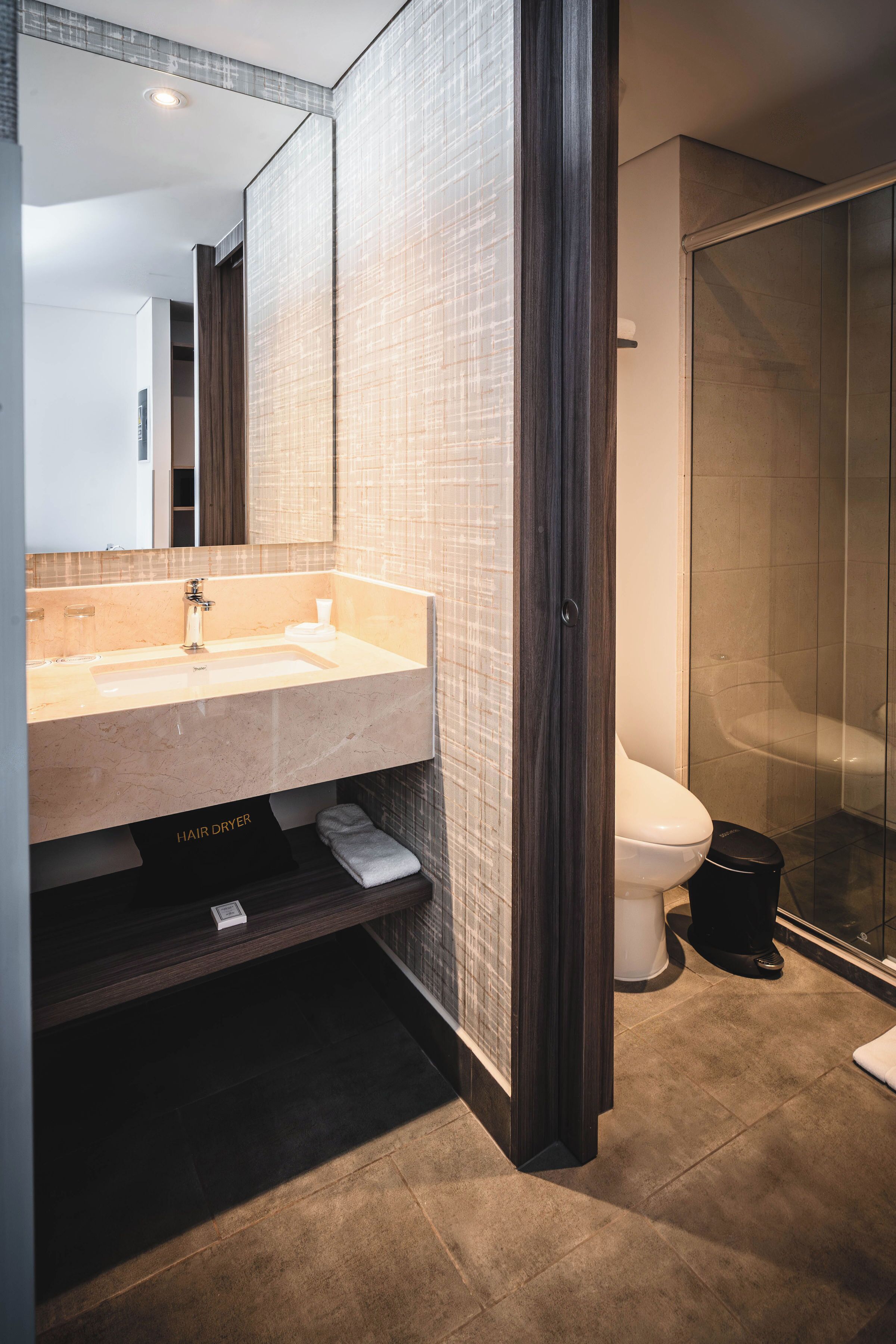 Un baño moderno con un espejo grande, un lavabo, un inodoro y una zona de ducha.
