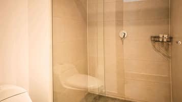 A modern bathroom with a glass-enclosed shower, a toilet, and a towel rack.