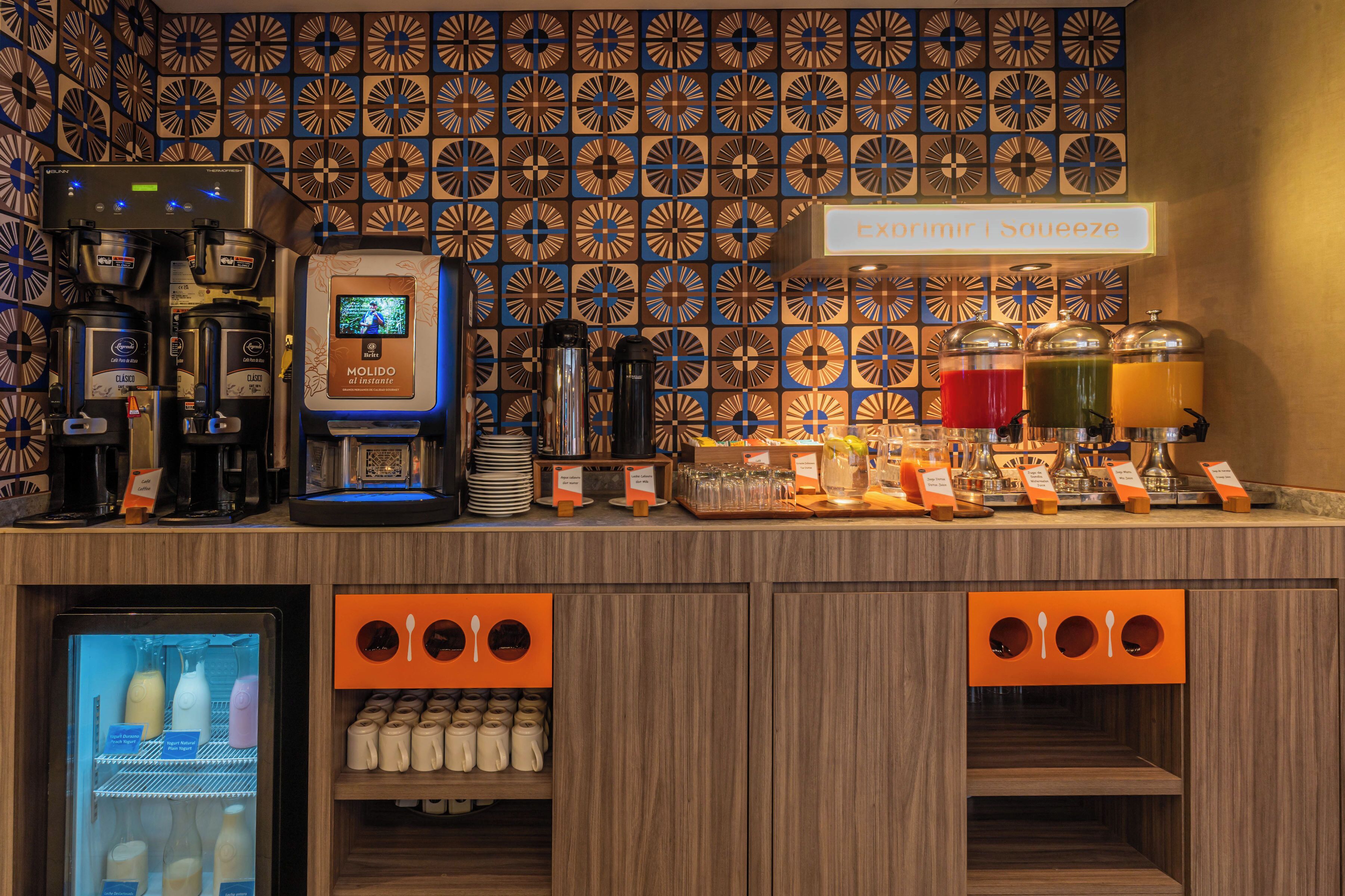 A coffee station with multiple coffee machines, a beverage dispenser, and a refrigerated display.