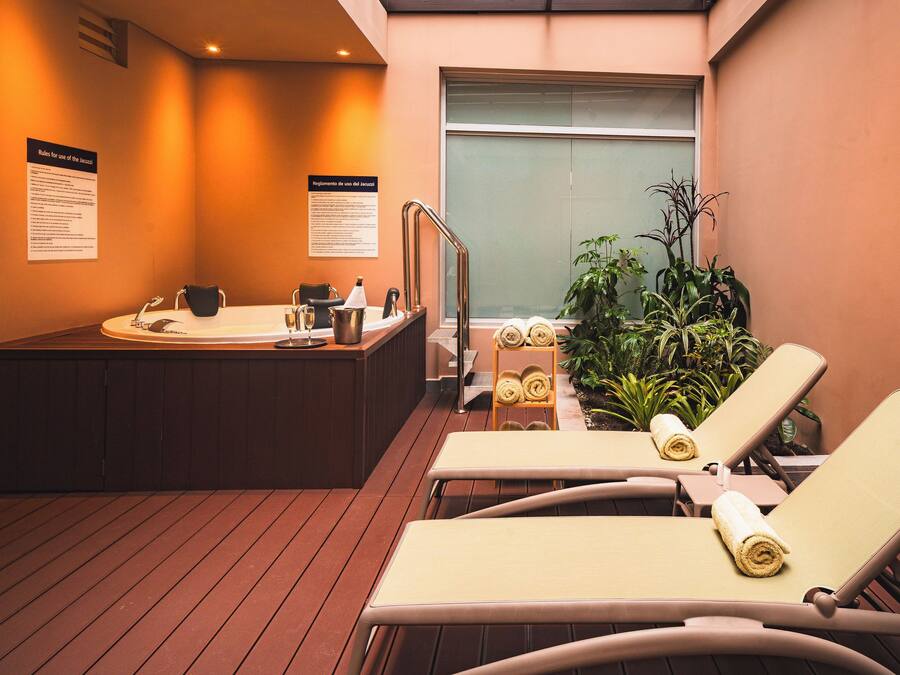 Un área de spa con camilla de masaje, sillón de masajes, un lavamanos pequeño y un perchero para toallas.