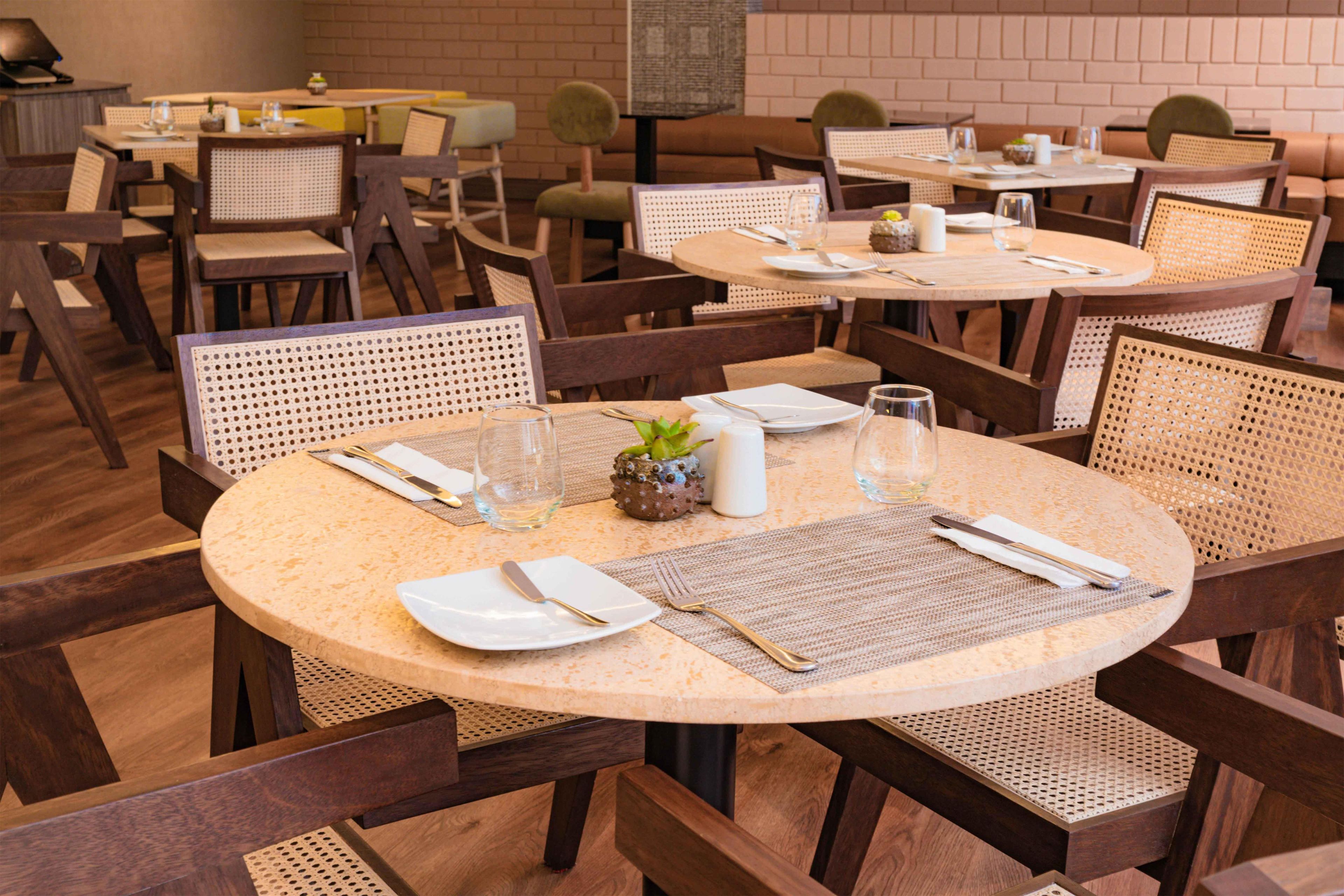 Ein Restaurant mit runden Tischen, Stühlen und einer Ziegelwand im Hintergrund.