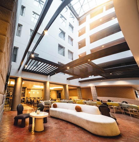 A spacious indoor area with a high ceiling, multiple seating arrangements, and a central column.