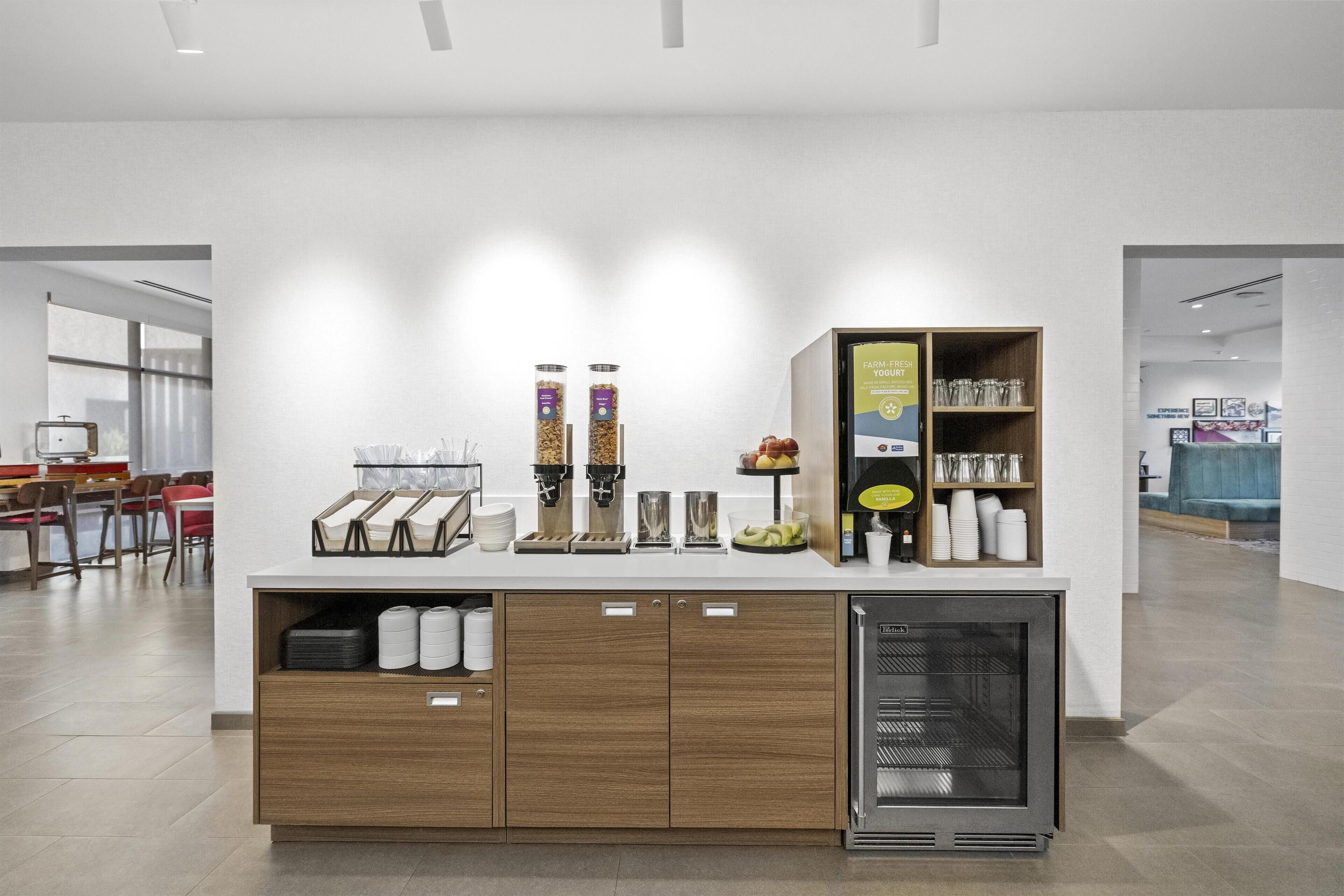 A modern kitchen area with a coffee station, a refrigerator, and a buffet setup.