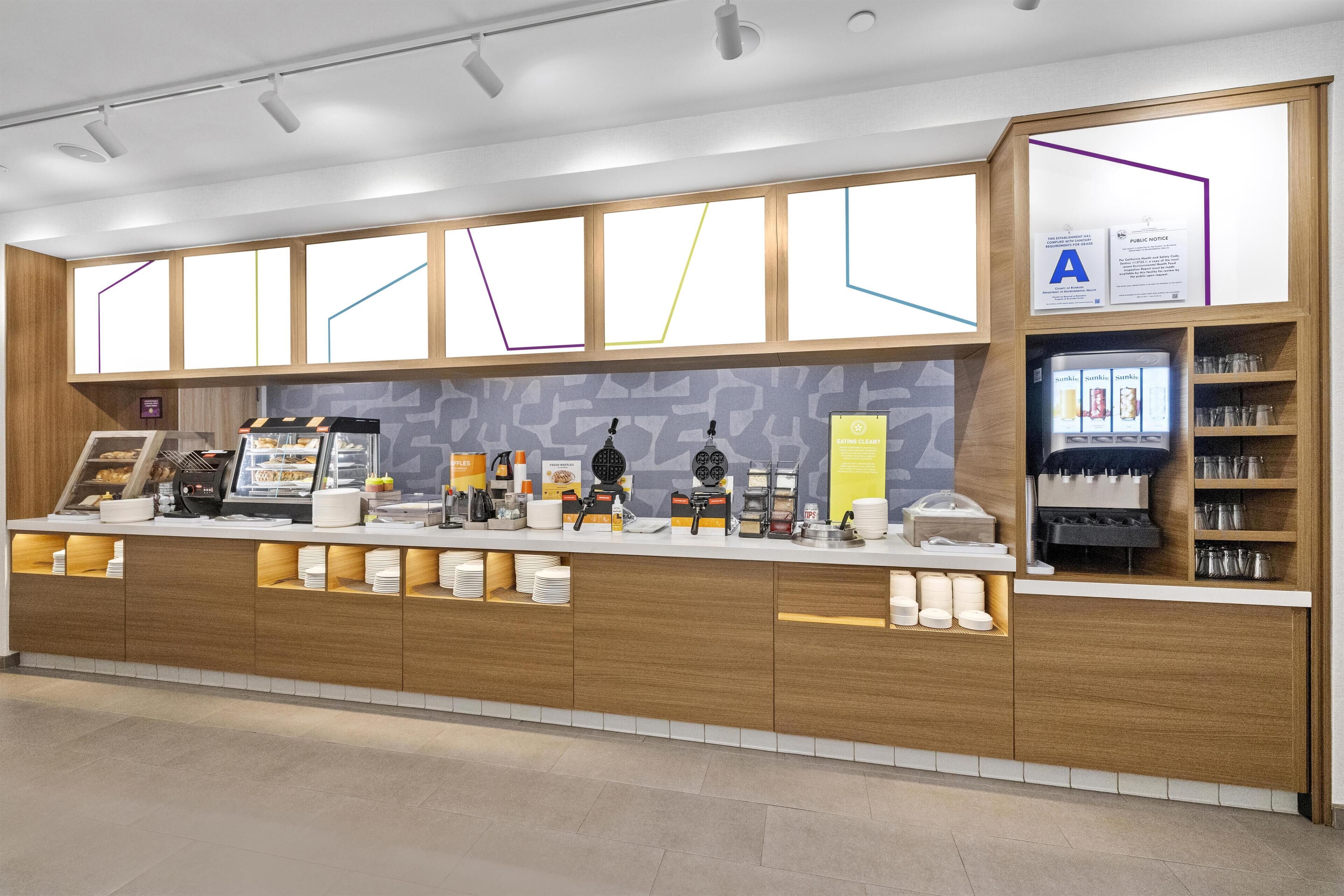 Una cafetería moderna con mostrador de madera, máquinas de café y una variedad de alimentos.