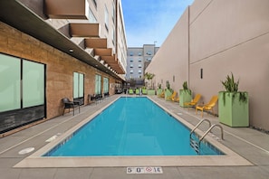 A swimming pool with a 5'0" depth marker, surrounded by lounge chairs and potted plants.