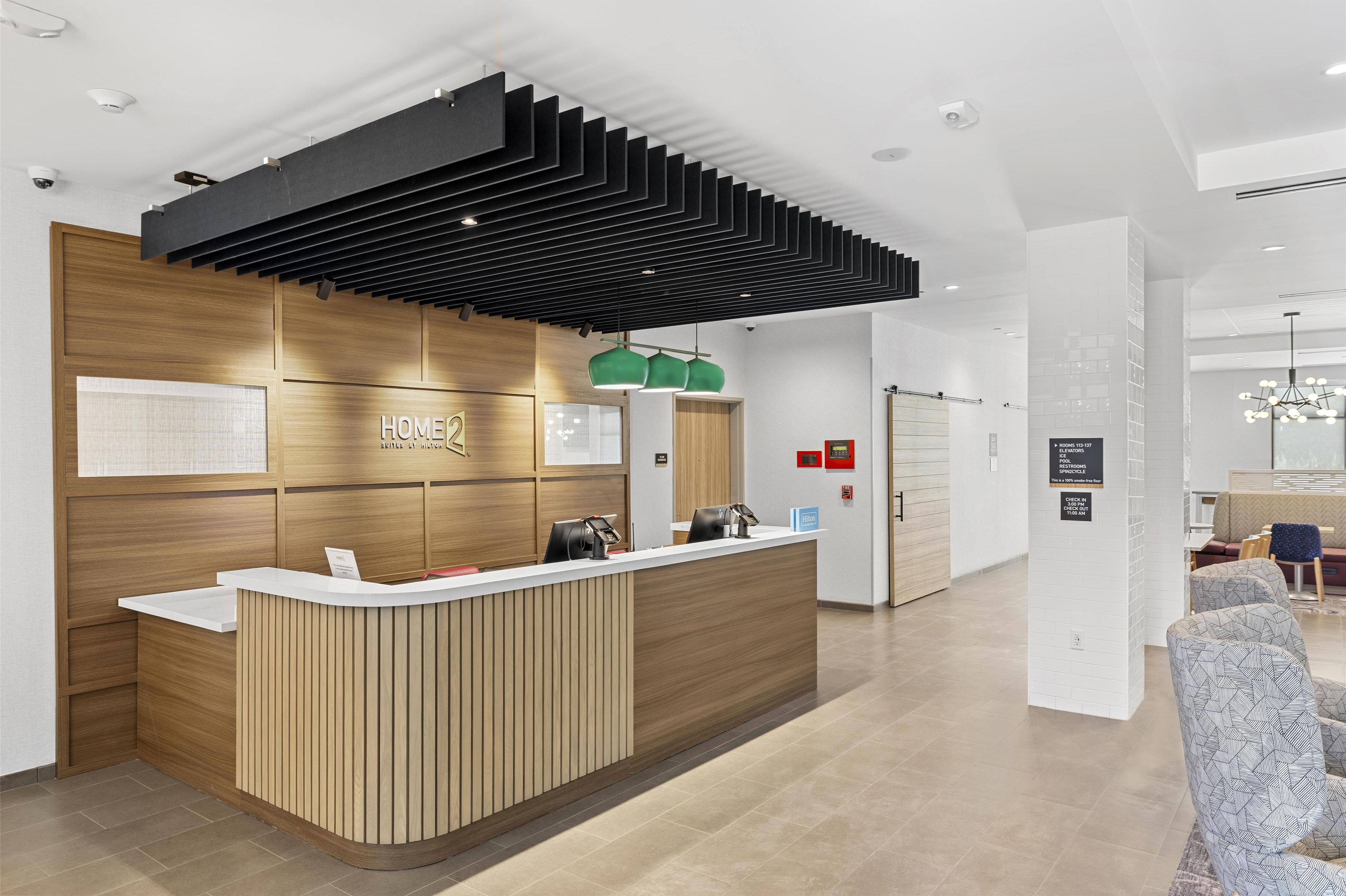 Un comptoir d’accueil moderne avec un revêtement en bois et un panneau supérieur noir.