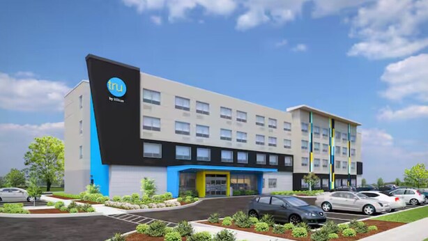 A modern hotel building with a prominent 'tru' logo, a central entrance, and a parking area with several cars. - Tru By Hilton Santa Rosa Beach (Santa Rosa Beach)