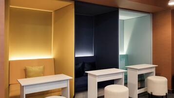 Una habitación moderna con sofá, dos mesas blancas y un taburete redondo.