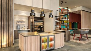 A modern bar area with a central island, shelves with bottles, and a foosball table. - Homewood Suites By Hilton Saltillo (Saltillo)