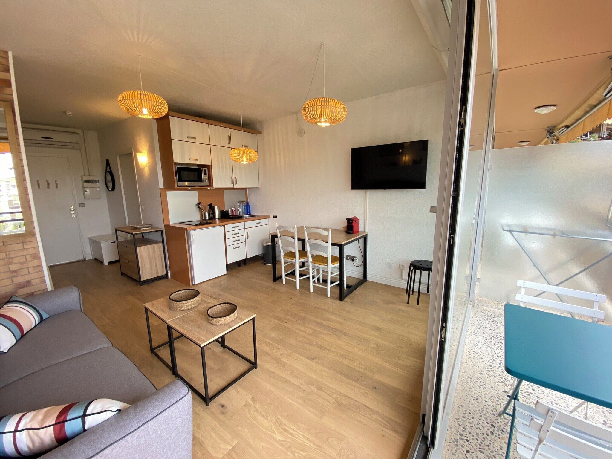 A compact living space with a kitchenette, a dining area, and a seating area with a sofa and a small table.