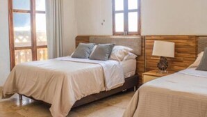 Een slaapkamer met een bed, nachtkastje en raam.