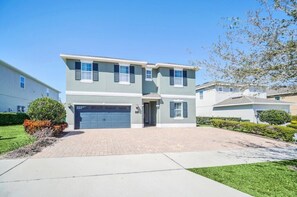 A two-story residential building with a garage, a driveway, and a well-maintained lawn.