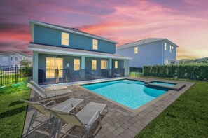 A modern two-story house with a swimming pool, outdoor seating, and a well-maintained lawn.