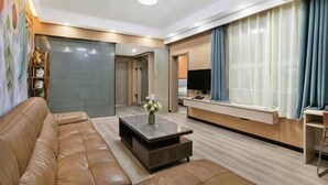 Een moderne woonkamer met een leren bank, een salontafel, een flatscreen televisie en een groot raam met gordijnen.