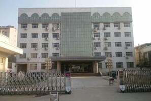 A multi-story building with a central entrance, air conditioning units, and a parking area with bicycles. - Xunxian Guest House (Hebi Xunxian Ancient City Branch) (Xun County)