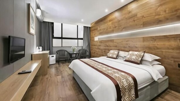 Een moderne hotelkamer met een groot bed, een bureau, een televisie en een raam met gordijnen.