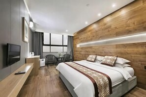 Une chambre d’hôtel moderne équipée d’un grand lit, d’un bureau, d’une télévision et d’une fenêtre avec des rideaux.