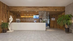 Een receptie met een houten receptiebalie, een potplant en een modern interieur.
