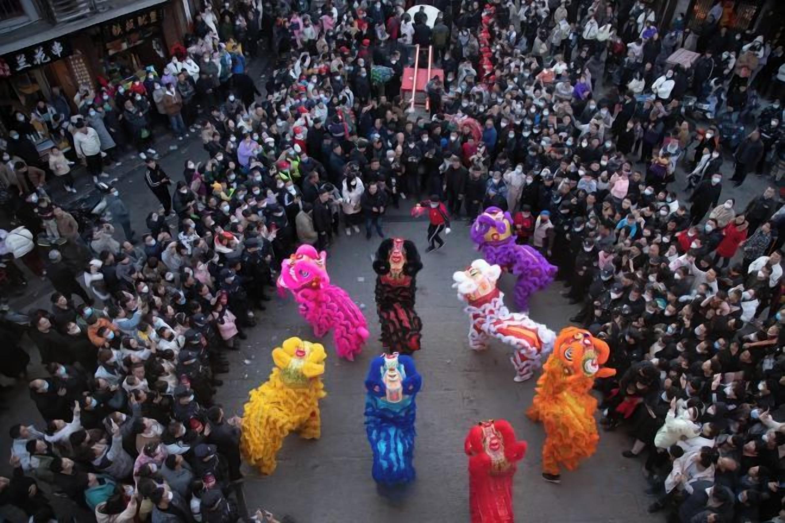 A crowded street with a group of people in colorful costumes.