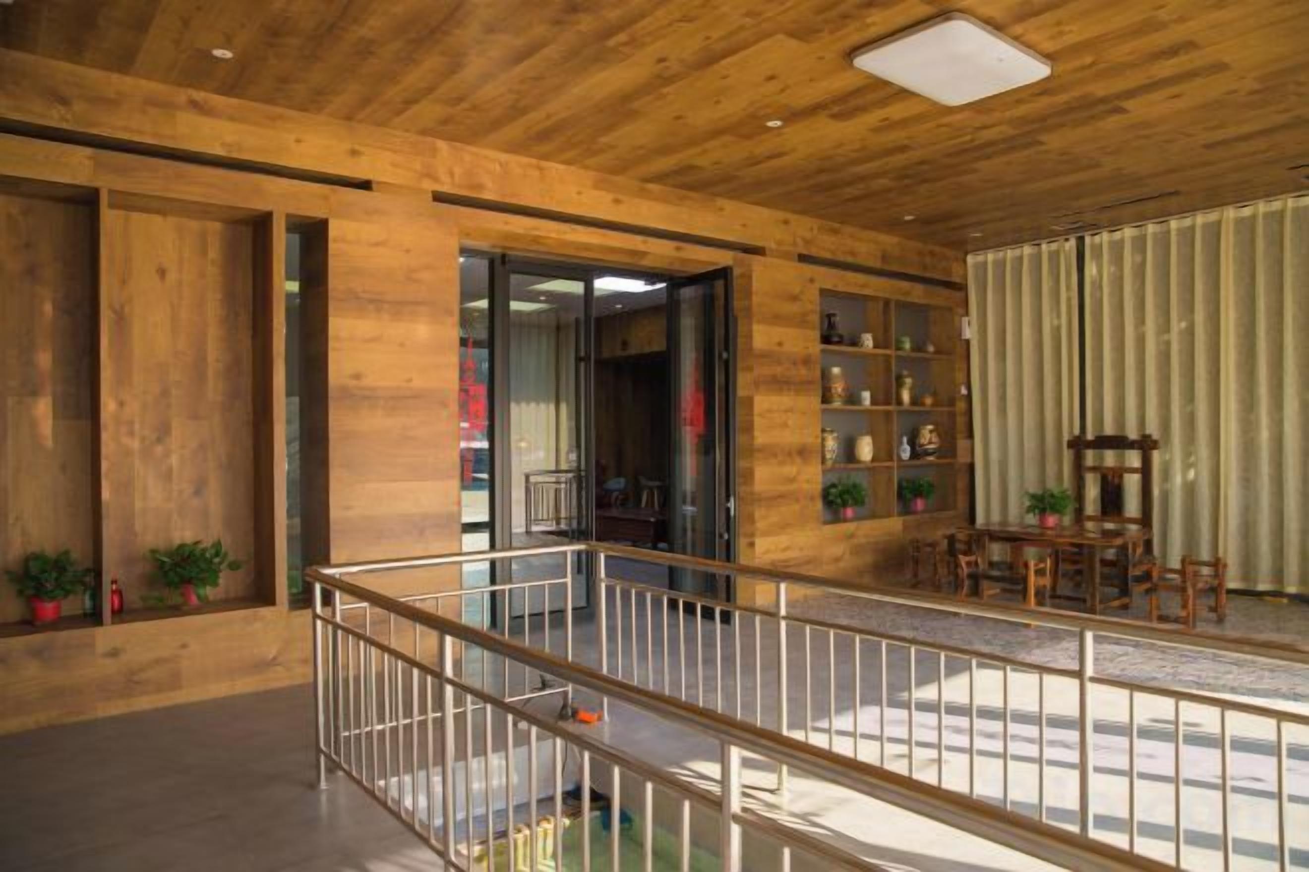 A wooden interior with a balcony, a staircase, and a seating area with chairs and a table.