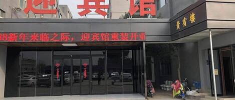 A hotel entrance with a large sign and a glass door.