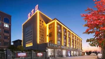 A hotel with a prominent sign, multiple floors, and a well-lit facade.