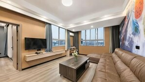 Een moderne woonkamer met een grote flatscreen televisie, een leren bank, een salontafel en een muurschildering.