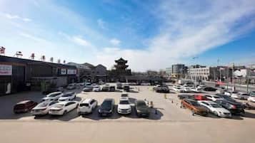 Un parcheggio con diverse automobili e una struttura simile a un pagode sullo sfondo.