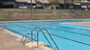 A swimming pool with a metal ladder and a 'NO DIVING' sign, surrounded by a fence with houses in the background. - Modern/Retro 1br Condo by Exceptional Stays (High Point)