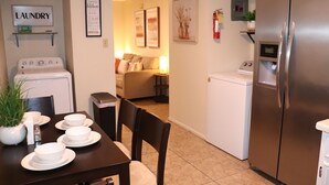 A kitchen with a refrigerator, washing machine, and a dining area with a table set for four.