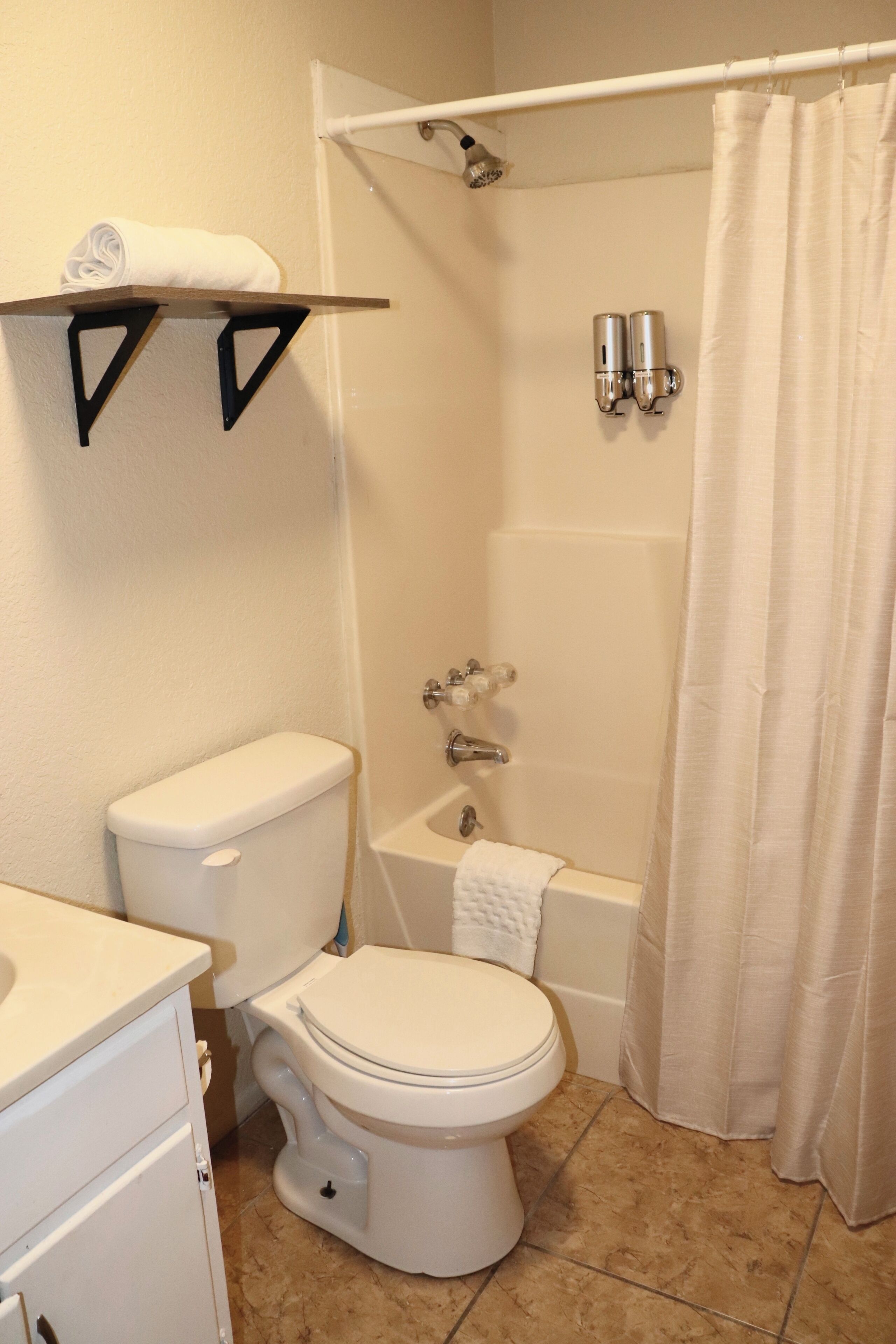 Un baño con inodoro, bañera, ducha y un perchero para toallas.