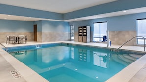 Una piscina interna con acqua cristallina, un'area relax con poltrone e una reception.