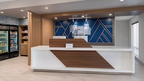Una reception dal design moderno, una parete geometrica blu e, alla sinistra, una vetrina refrigerata.