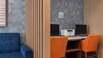 Ein Business-Center mit zwei Schreibtischen, jeweils ausgestattet mit einem Computer und Drucker, sowie zwei orangefarbenen Stühlen.
