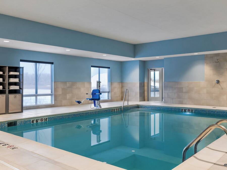 Une piscine intérieure à l’eau claire, aux couleurs bleu et beige, et dotée d’un poste de surveillance pour les sauveteurs.