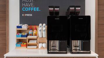 Two coffee machines on a counter with coffee pods, cups, and a sign that reads "MUST. HAVE. COFFEE."