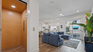 Una sala de estar moderna con un sofá seccional, un comedor y una cocina al fondo.
