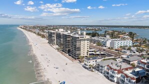 Un paisaje urbano costero con una playa, rascacielos y un puerto deportivo.