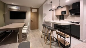 A modern kitchen with a dining area, bar stools, and a TV mounted on the wall. - Relax in Flandes Tolima, apartment with Swimming Pool (Flandes)
